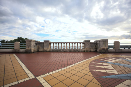 Railing on the balcony in a promenade, framing the sea, with a cloudy sky above, on a winter dayの写真素材
