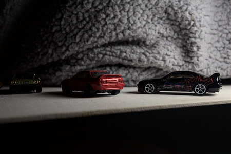 Mantua, Italy - 3RD JANUARY 2025 - Hot Wheels replicas of various Nissan Skyline models, two R30, a GT-R R32 and a GT-R R33, on a white board, next to a gray piece of fabric, pretending to have a race on a mountain road by the edge of a cliffのeditorial素材