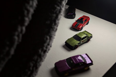 Mantua, Italy - 3RD JANUARY 2025 - Hot Wheels replicas of various Nissan Skyline models, two R30, a GT-R R32 and a GT-R R33, on a white board, next to a gray piece of fabric, pretending to have a race on a mountain road by the edge of a cliffのeditorial素材