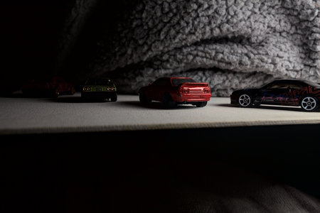 Mantua, Italy - 3RD JANUARY 2025 - Hot Wheels replicas of various Nissan Skyline models, two R30, a GT-R R32 and a GT-R R33, on a white board, next to a gray piece of fabric, pretending to have a race on a mountain road by the edge of a cliffのeditorial素材
