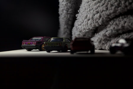 Mantua, Italy - 3RD JANUARY 2025 - Hot Wheels replicas of various Nissan Skyline models, two R30, a GT-R R32 and a GT-R R33, on a white board, next to a gray piece of fabric, pretending to have a race on a mountain road by the edge of a cliffのeditorial素材