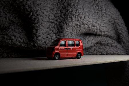 Mantua, Italy - 3RD JANUARY 2025 - Takara Tomy replica of a Suzuki Every in japanese postal service livery on a white board, next to a gray piece of fabric, pretending to travel on a mountain road by the edge of a cliffのeditorial素材