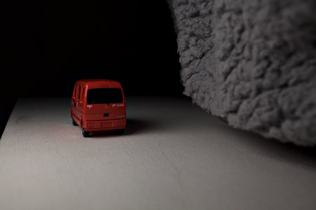 Mantua, Italy - 3RD JANUARY 2025 - Takara Tomy replica of a Suzuki Every in japanese postal service livery on a white board, next to a gray piece of fabric, pretending to travel on a mountain road by the edge of a cliffのeditorial素材
