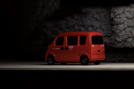 Mantua, Italy - 3RD JANUARY 2025 - Takara Tomy replica of a Suzuki Every in japanese postal service livery on a white board, next to a gray piece of fabric, pretending to travel on a mountain road by the edge of a cliffのeditorial素材
