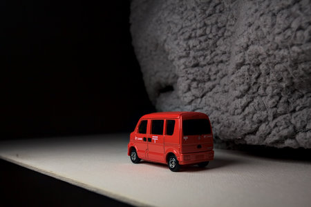 Mantua, Italy - 3RD JANUARY 2025 - Takara Tomy replica of a Suzuki Every in japanese postal service livery on a white board, next to a gray piece of fabric, pretending to travel on a mountain road by the edge of a cliffのeditorial素材