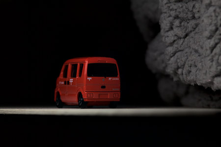 Mantua, Italy - 3RD JANUARY 2025 - Takara Tomy replica of a Suzuki Every in japanese postal service livery on a white board, next to a gray piece of fabric, pretending to travel on a mountain road by the edge of a cliffのeditorial素材