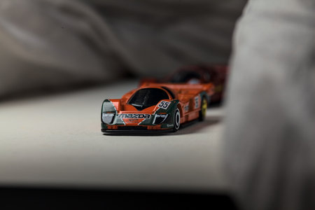 Mantua, Italy - 4TH JANUARY 2025 - Hot Wheels replicas of two Mazda 787B in race livery on white board, bordered by white rolls of fabric, pretending to make a curve on a road and having a race between themのeditorial素材