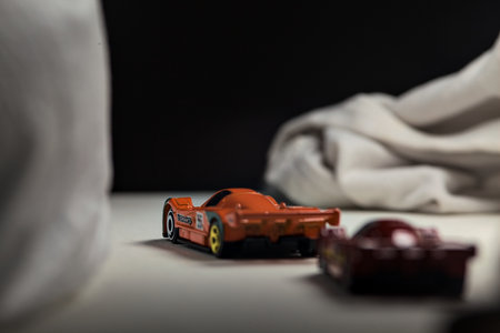 Mantua, Italy - 4TH JANUARY 2025 - Hot Wheels replicas of two Mazda 787B in race livery on white board, bordered by white rolls of fabric, pretending to make a curve on a road and having a race between themのeditorial素材