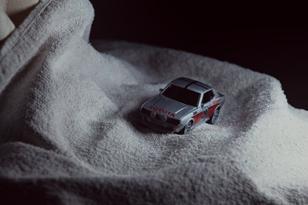 Mantua, Italy - 10TH JANUARY 2025 - Majorette replica of a Toyota Celica GT Coupe pretending to run a rally on a snowy road, next to a cliff, in the mountainsのeditorial素材