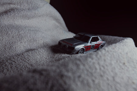 Mantua, Italy - 10TH JANUARY 2025 - Majorette replica of a Toyota Celica GT Coupe pretending to run a rally on a snowy road, next to a cliff, in the mountainsのeditorial素材