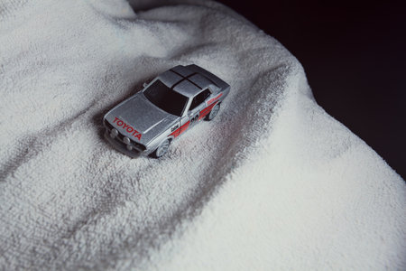 Mantua, Italy - 10TH JANUARY 2025 - Majorette replica of a Toyota Celica GT Coupe pretending to run a rally on a snowy road, next to a cliff, in the mountainsのeditorial素材