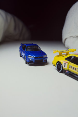 Mantua, Italy - 10TH JANUARY 2025 - Takara Tomy replicas of a Nissan Skyline GT-R V-Spec II Nur and a 1998 Nissan Skyline GT-R R33 in #23 Pennzoil Nismo yellow and black livery pretending to have a race, on a curve of a circuitのeditorial素材