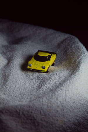 Mantua, Italy - 10TH JANUARY 2025 - Mini GT replica of a yellow Lancia Stratos HF Stradale pretending to run a rally on a snowy road, next to a cliff, in the mountainsのeditorial素材
