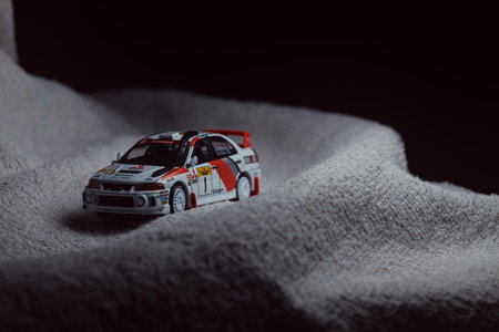 Mantua, Italy - 10TH JANUARY 2025 - Pop Race replica of a 1998 Mitsubishi Lancer Evolution IV in Safari Rally of Kenya #1 livery and car trim pretending to run a rally on a snowy road, next to a cliff, in the mountainsのeditorial素材