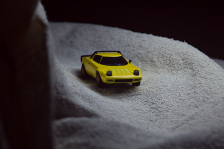 Mantua, Italy - 10TH JANUARY 2025 - Mini GT replica of a yellow Lancia Stratos HF Stradale pretending to run a rally on a snowy road, next to a cliff, in the mountainsのeditorial素材