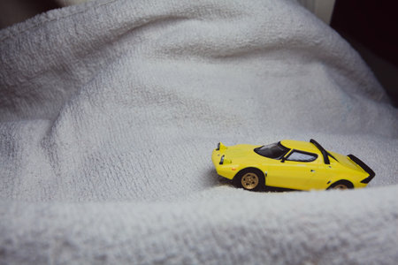 Mantua, Italy - 10TH JANUARY 2025 - Mini GT replica of a yellow Lancia Stratos HF Stradale pretending to run a rally on a snowy road, next to a cliff, in the mountainsのeditorial素材