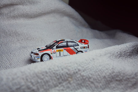 Mantua, Italy - 10TH JANUARY 2025 - Pop Race replica of a 1998 Mitsubishi Lancer Evolution IV in Safari Rally of Kenya #1 livery and car trim pretending to run a rally on a snowy road, next to a cliff, in the mountainsのeditorial素材