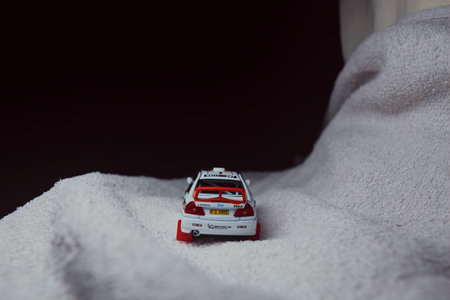 Mantua, Italy - 10TH JANUARY 2025 - Pop Race replica of a 1998 Mitsubishi Lancer Evolution IV in Safari Rally of Kenya #1 livery and car trim pretending to run a rally on a snowy road, next to a cliff, in the mountainsのeditorial素材