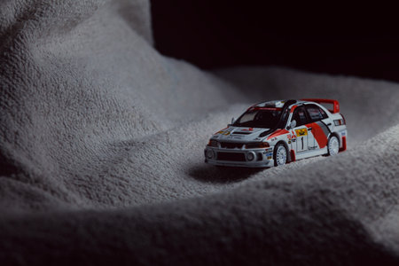 Mantua, Italy - 10TH JANUARY 2025 - Pop Race replica of a 1998 Mitsubishi Lancer Evolution IV in Safari Rally of Kenya #1 livery and car trim pretending to run a rally on a snowy road, next to a cliff, in the mountainsのeditorial素材