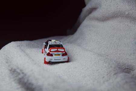Mantua, Italy - 10TH JANUARY 2025 - Pop Race replica of a 1998 Mitsubishi Lancer Evolution IV in Safari Rally of Kenya #1 livery and car trim pretending to run a rally on a snowy road, next to a cliff, in the mountainsのeditorial素材
