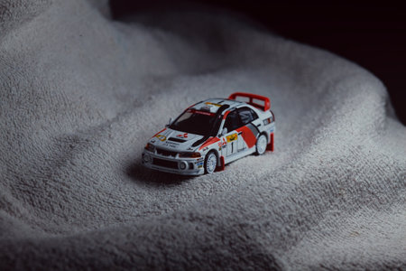Mantua, Italy - 10TH JANUARY 2025 - Pop Race replica of a 1998 Mitsubishi Lancer Evolution IV in Safari Rally of Kenya #1 livery and car trim pretending to run a rally on a snowy road, next to a cliff, in the mountainsのeditorial素材