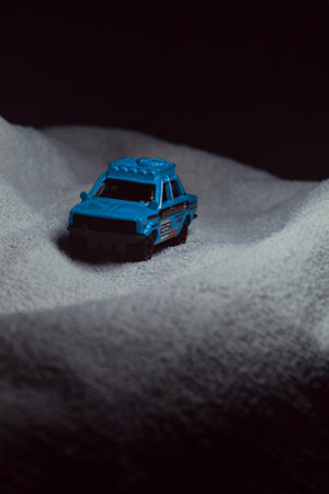 Mantua, Italy - 10TH JANUARY 2025 - Matchbox replica of a 1970 Datsun 510 in rally livery and trim pretending to run a rally on a snowy road, next to a cliff, in the mountainsのeditorial素材
