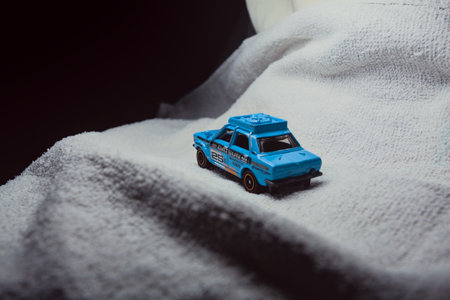 Mantua, Italy - 10TH JANUARY 2025 - Matchbox replica of a 1970 Datsun 510 in rally livery and trim pretending to run a rally on a snowy road, next to a cliff, in the mountainsのeditorial素材