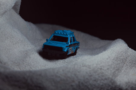 Mantua, Italy - 10TH JANUARY 2025 - Matchbox replica of a 1970 Datsun 510 in rally livery and trim pretending to run a rally on a snowy road, next to a cliff, in the mountainsのeditorial素材