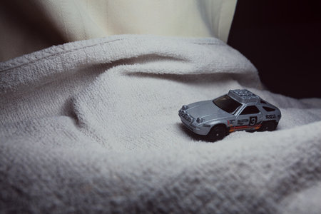 Mantua, Italy - 10TH JANUARY 2025 - Hot Wheels replica of a Porsche 928S Safari in rally livery and trim pretending to run a rally on a snowy road, next to a cliff, in the mountainsのeditorial素材