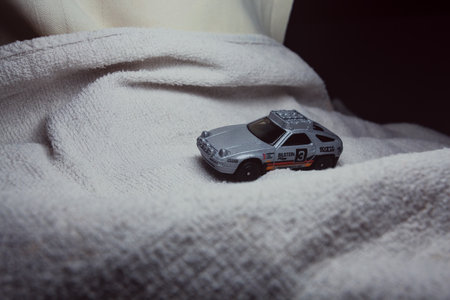 Mantua, Italy - 10TH JANUARY 2025 - Hot Wheels replica of a Porsche 928S Safari in rally livery and trim pretending to run a rally on a snowy road, next to a cliff, in the mountainsのeditorial素材