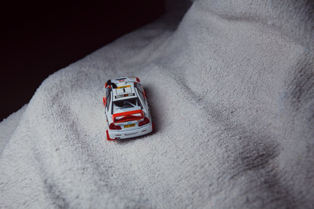 Mantua, Italy - 10TH JANUARY 2025 - Pop Race replica of a 1998 Mitsubishi Lancer Evolution IV in Safari Rally of Kenya #1 livery and car trim pretending to run a rally on a snowy road, next to a cliff, in the mountainsのeditorial素材