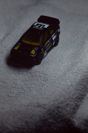 Mantua, Italy - 10TH JANUARY 2025 - Hot Wheels replica of a Ford Escort in black livery and rally trim pretending to run a rally on a snowy road, next to a cliff, in the mountainsのeditorial素材
