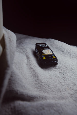 Mantua, Italy - 10TH JANUARY 2025 - Hot Wheels replica of a Ford Escort in black livery and rally trim pretending to run a rally on a snowy road, next to a cliff, in the mountainsのeditorial素材