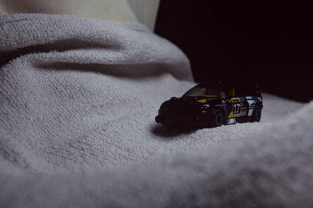 Mantua, Italy - 10TH JANUARY 2025 - Hot Wheels replica of a Ford Escort in black livery and rally trim pretending to run a rally on a snowy road, next to a cliff, in the mountainsのeditorial素材