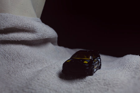 Mantua, Italy - 10TH JANUARY 2025 - Hot Wheels replica of a Ford Escort in black livery and rally trim pretending to run a rally on a snowy road, next to a cliff, in the mountainsのeditorial素材