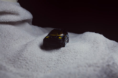 Mantua, Italy - 10TH JANUARY 2025 - Hot Wheels replica of a Ford Escort in black livery and rally trim pretending to run a rally on a snowy road, next to a cliff, in the mountainsのeditorial素材