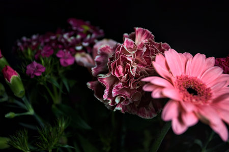 Pink toned bouquet with a pink rose, a pink gerbera and carnations in purple and pink, seen up...