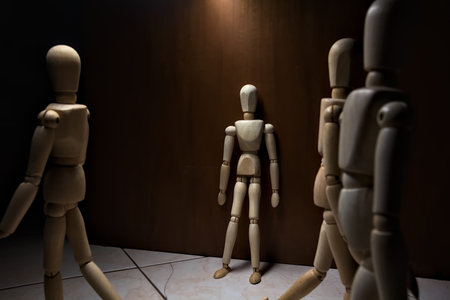 Wooden mannequin leaning against a wall pretending to watch and wait with other wooden mannequins in the act of passing byの写真素材