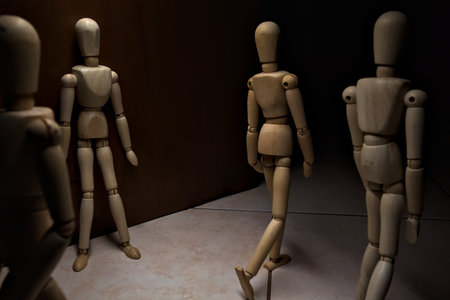 Wooden mannequin leaning against a wall with other wooden mannequins in the act of passing byの写真素材