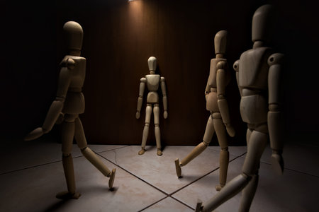 Wooden mannequin leaning against a wall with other wooden mannequins in the act of passing byの写真素材