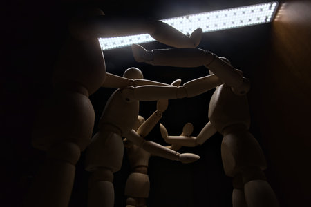 Wooden mannequin spreading its arms and standing against other three wooden mannequins pushing their...