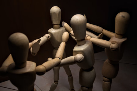 Wooden mannequin spreading its arms and standing against other three wooden mannequins pushing their...