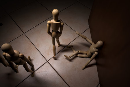 Wooden mannequin pretending to sit on a street and to lean on a wall raising his hand toward passing...