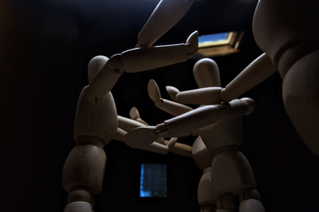 Wooden mannequin spreading its arms and standing against other three wooden mannequins pushing their...