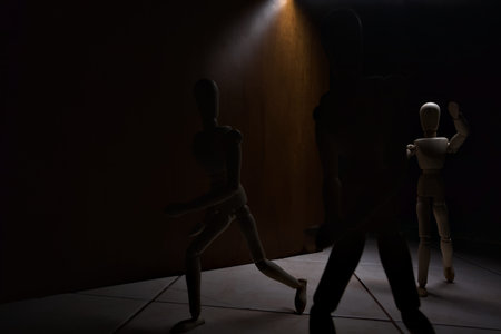 Wooden mannequin in the act of raising its arms and running towards other three mannequins in the act of escaping from itの写真素材