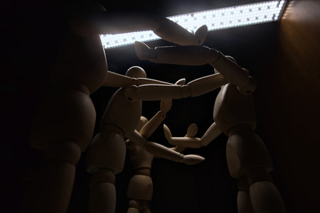 Wooden mannequin spreading its arms and standing against other three wooden mannequins pushing their...