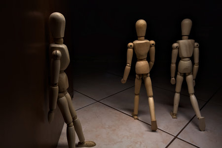 Wooden mannequin leaning against a wall with other wooden mannequins in the act of passing byの写真素材