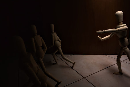 Wooden mannequin in the act of raising its arms and running towards other three mannequins in the act of escaping from itの写真素材