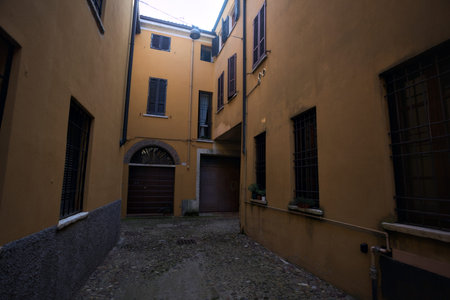 Narrow cobbled alley partially in the shade, ending in a corner, on a sunny day in an Italian town