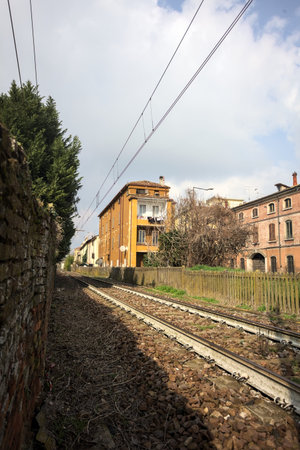 Railroad track passing next to a building by the edge of a road, on a sunny day in the Italian...